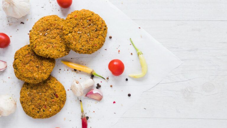 Burger vegetariani su sfondo chiaro con spezie e verdure estive. Ricetta antispreco estiva con legumi, dalla cucina ciociara.